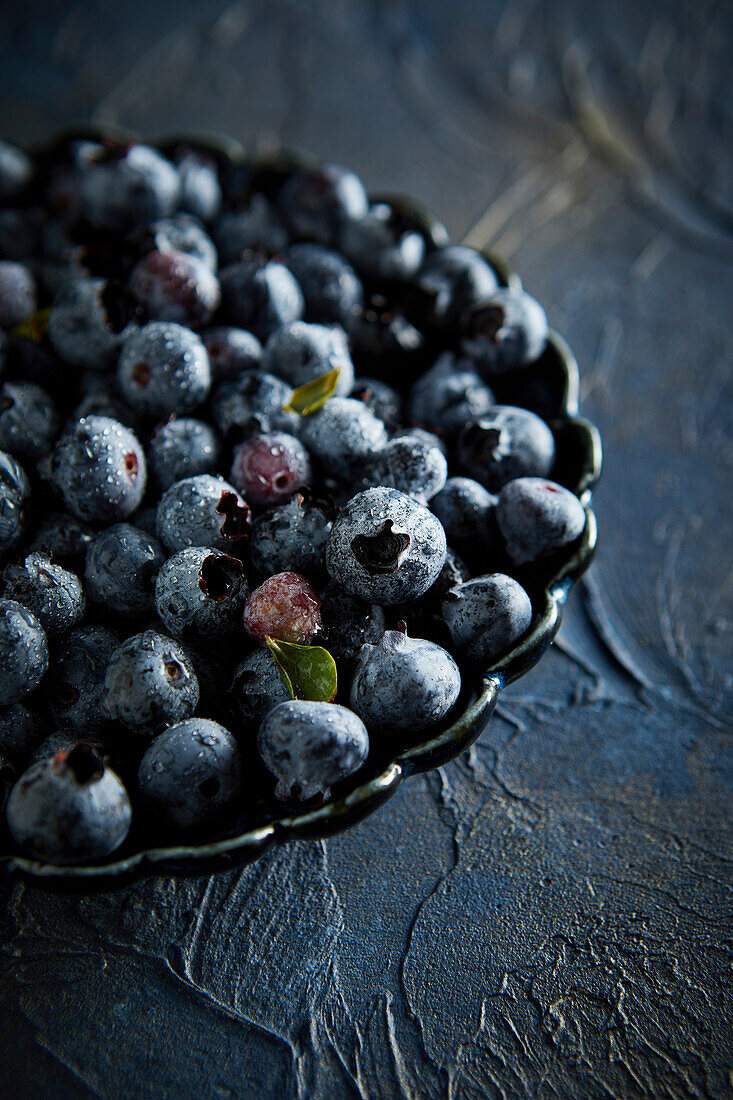 Blaubeeren mit Wassertröpfchen vor blauem Hintergrund