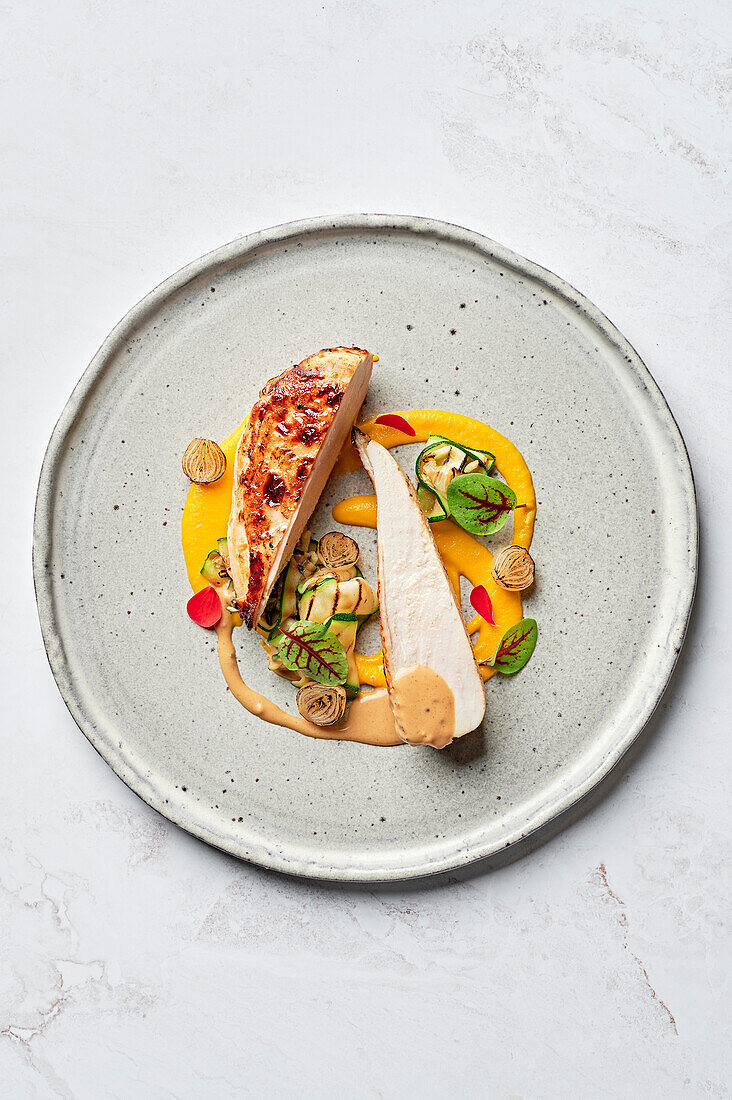 Chicken breast with lemon and oregano, carrot puree with citrus fruits, roasted pearl onions with caraway seeds, courgette shavings, mustard jus with grains