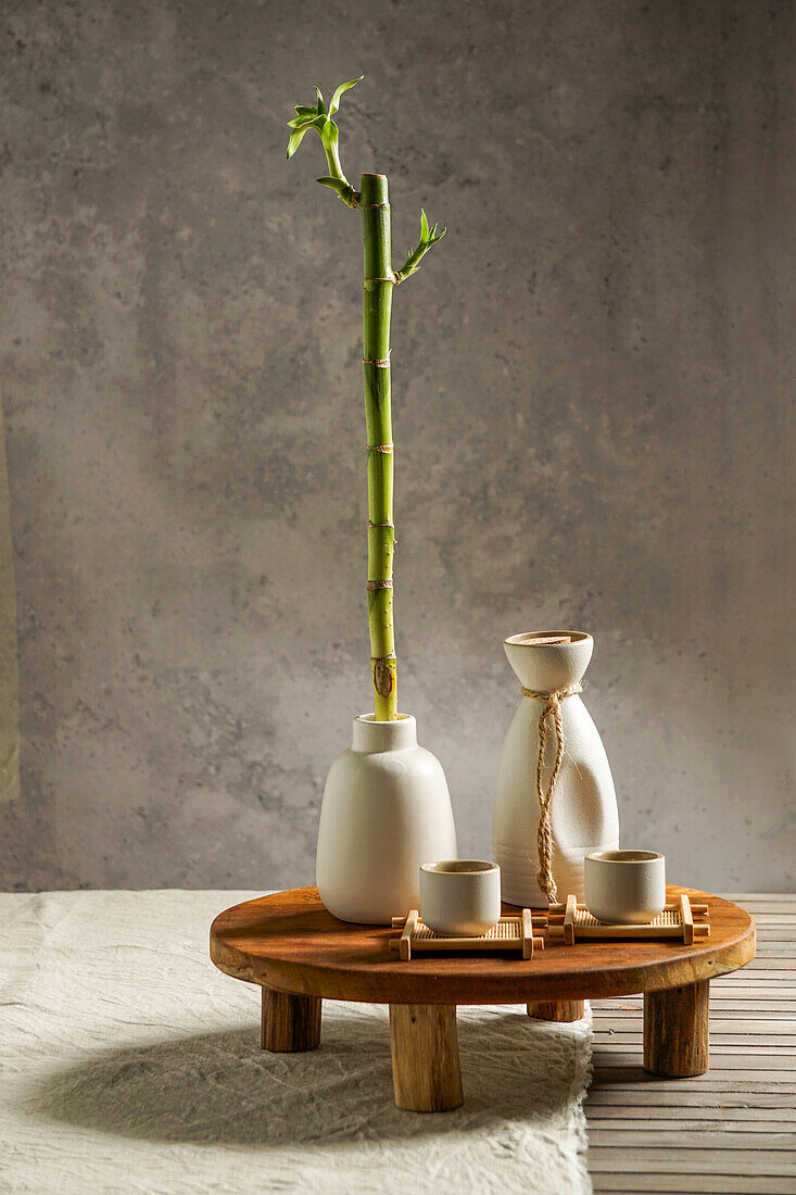 Japanese sake still life with a bamboo branch, light-coloured linen background, Asian ceremony