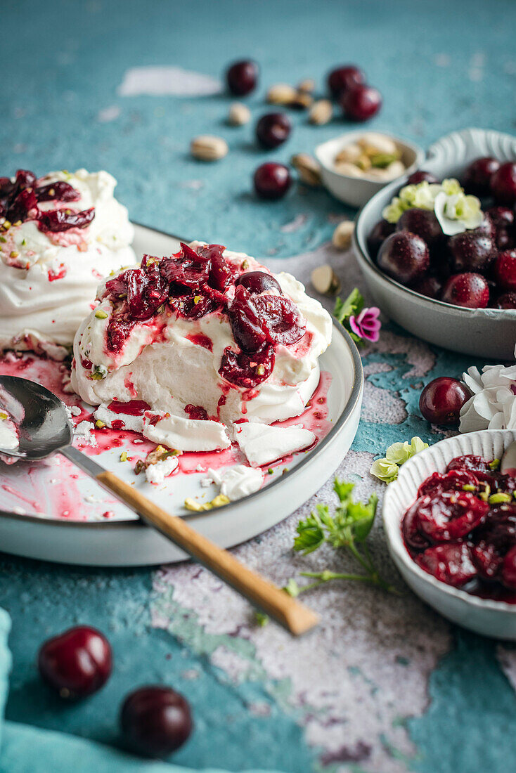 Meringues mit frischer Sahne und reifen Kirschen auf blauem Hintergrund