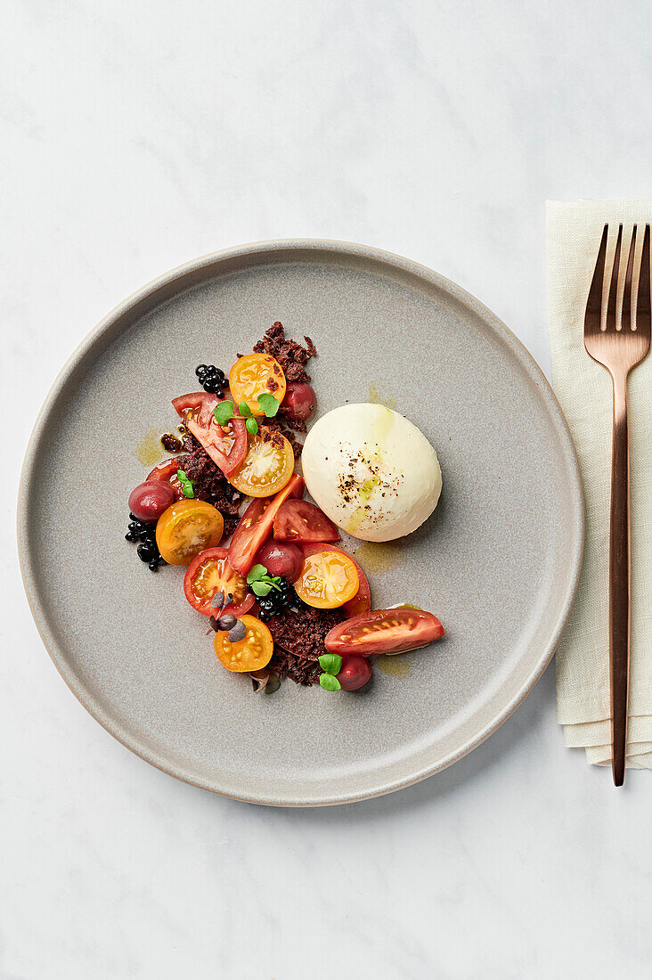 Burrata, heirloom tomatoes, balsamic caviar, cherry puree, olive and cornichon base