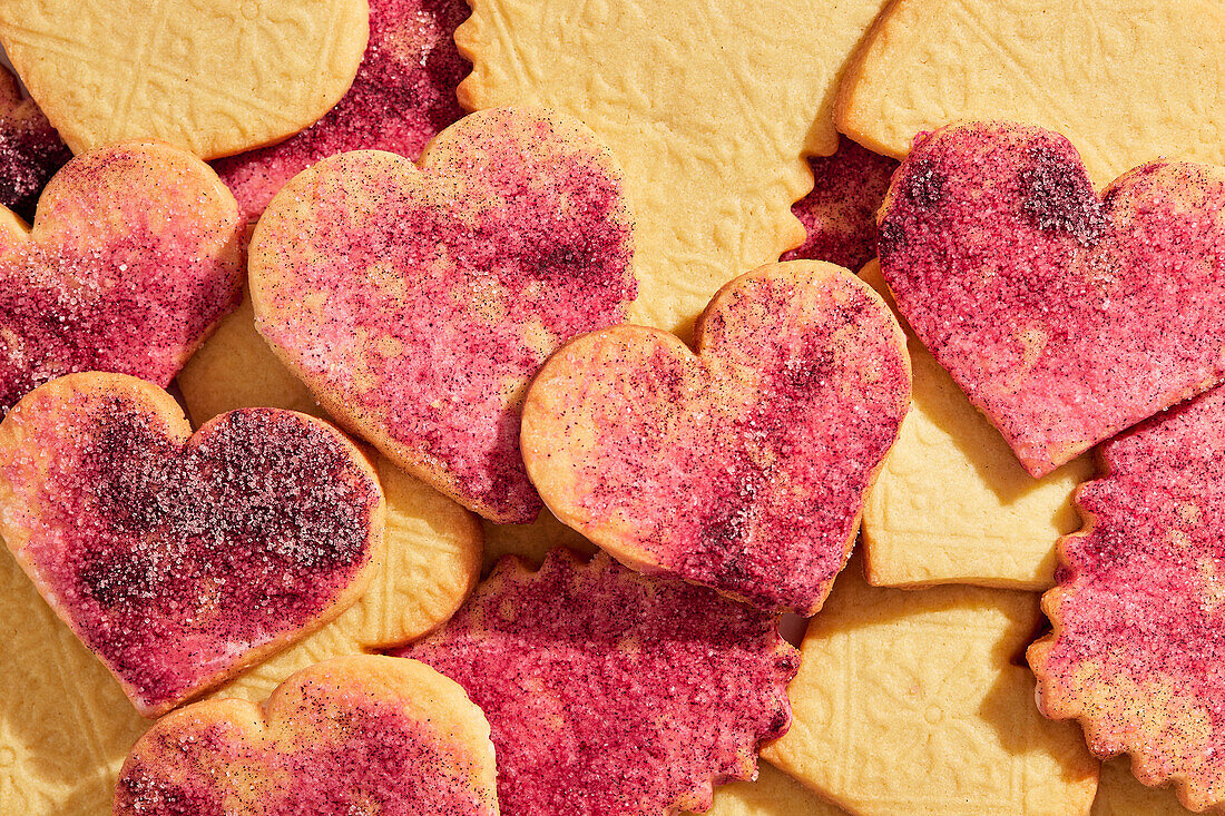 Punched out heart biscuits with pink sugar on a pink marble background