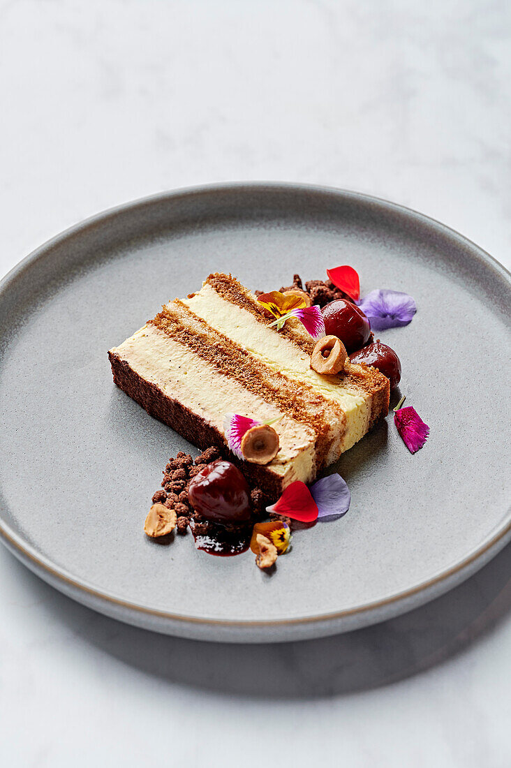 A slice of tiramisu with spiced cherry compote, salted chocolate sprinkles and candied hazelnuts