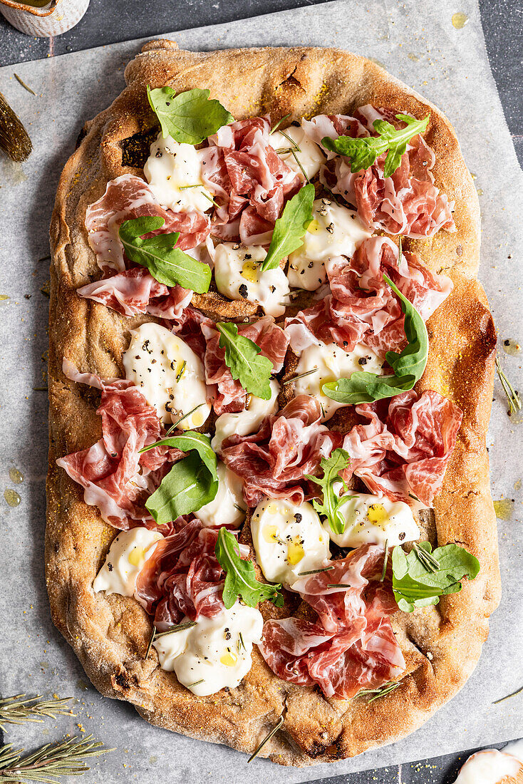Pizza with prosciutto, cheese and rocket leaves