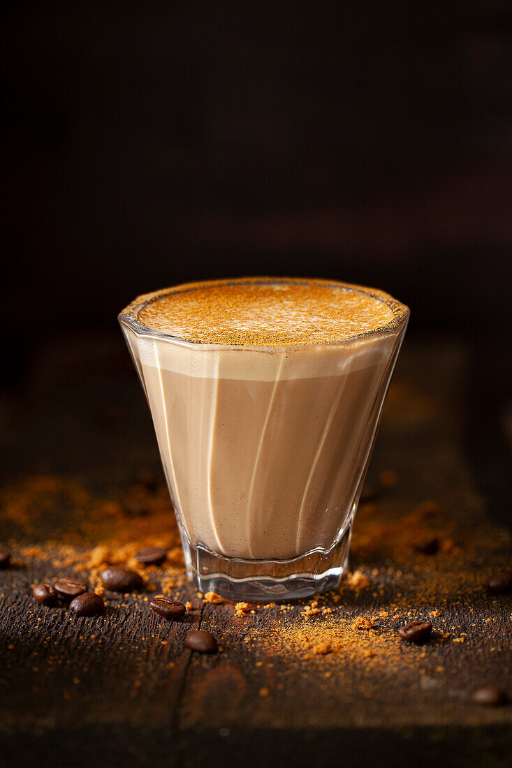 A heatproof glass with a sweet latte sprinkled with ground cinnamon