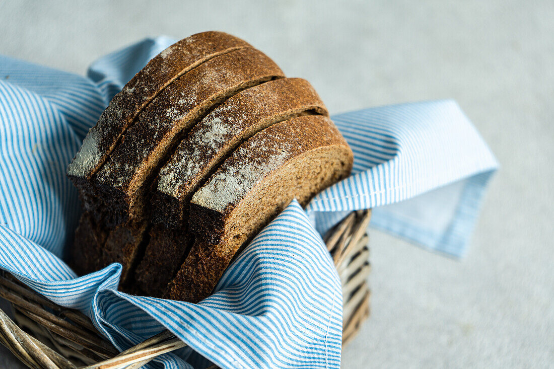 High angle of a stack of rye bread slices in a wicker basket with blue cloth napkin against a blurred light background