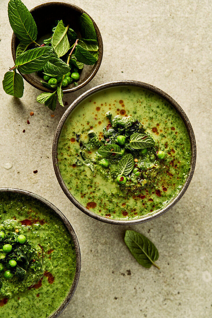 Pea, mint and kale soup on a light green background with chilli