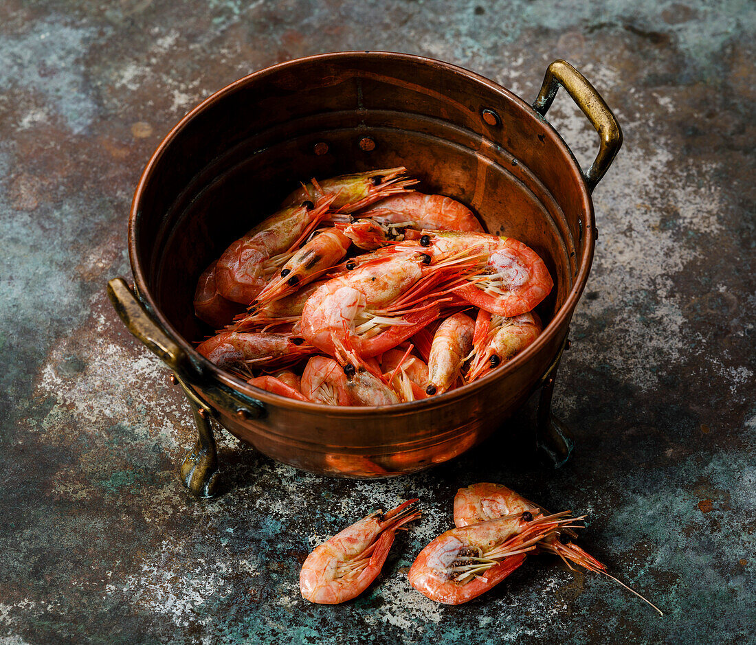 Cooked pink prawn in copper colander on metal background