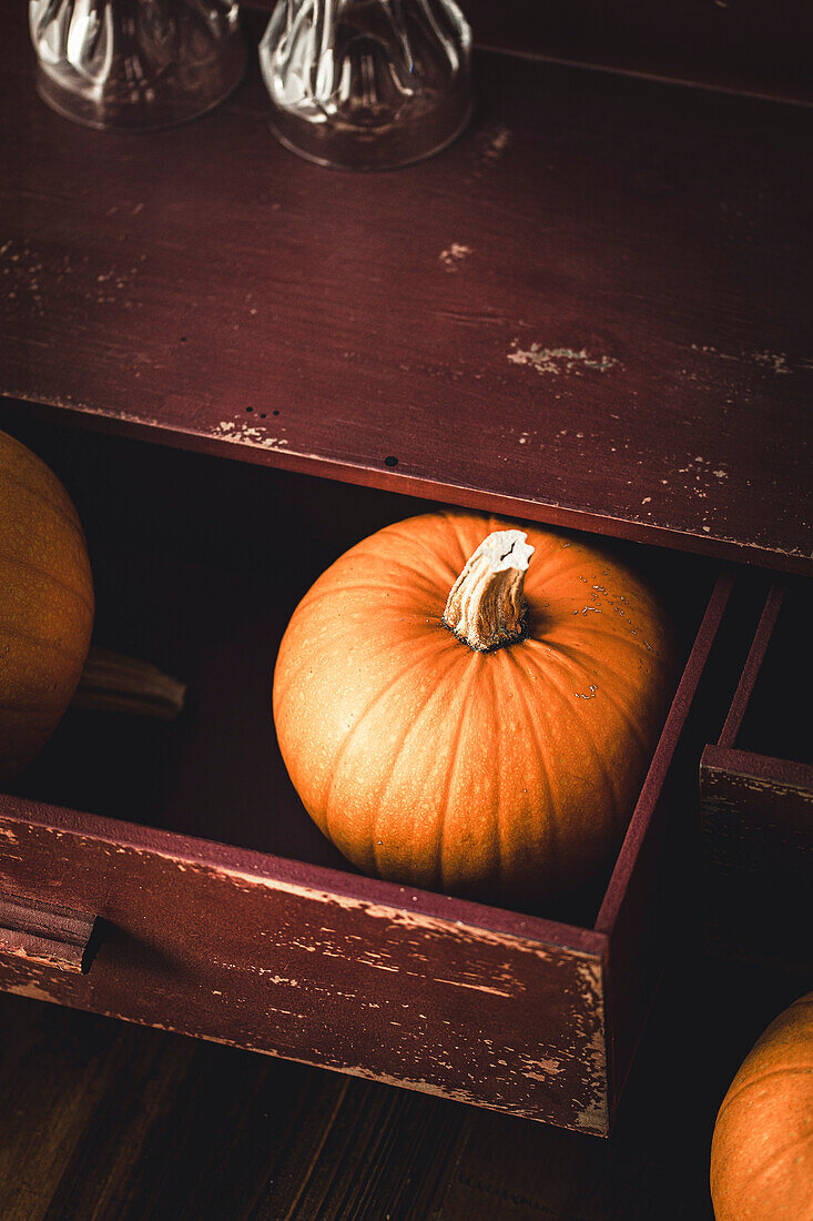A pumpkin in a drawer in a rustic kitchen