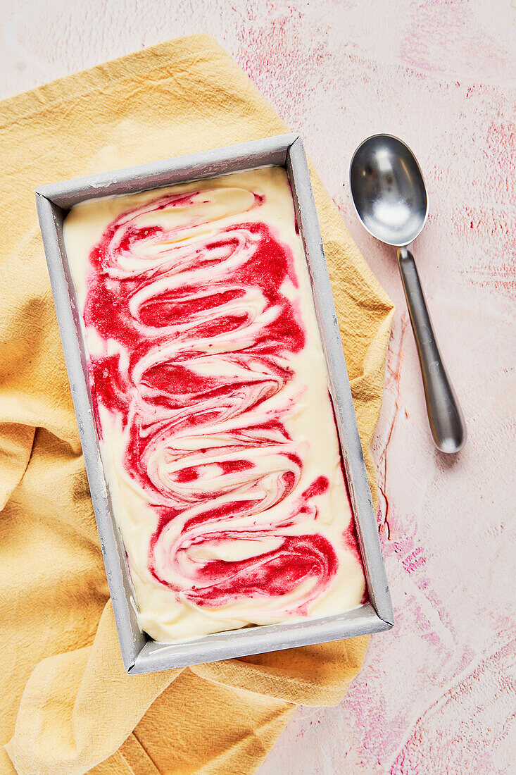 Raspberry Ripple Ice Cream Tub on pink background with yellow napkin