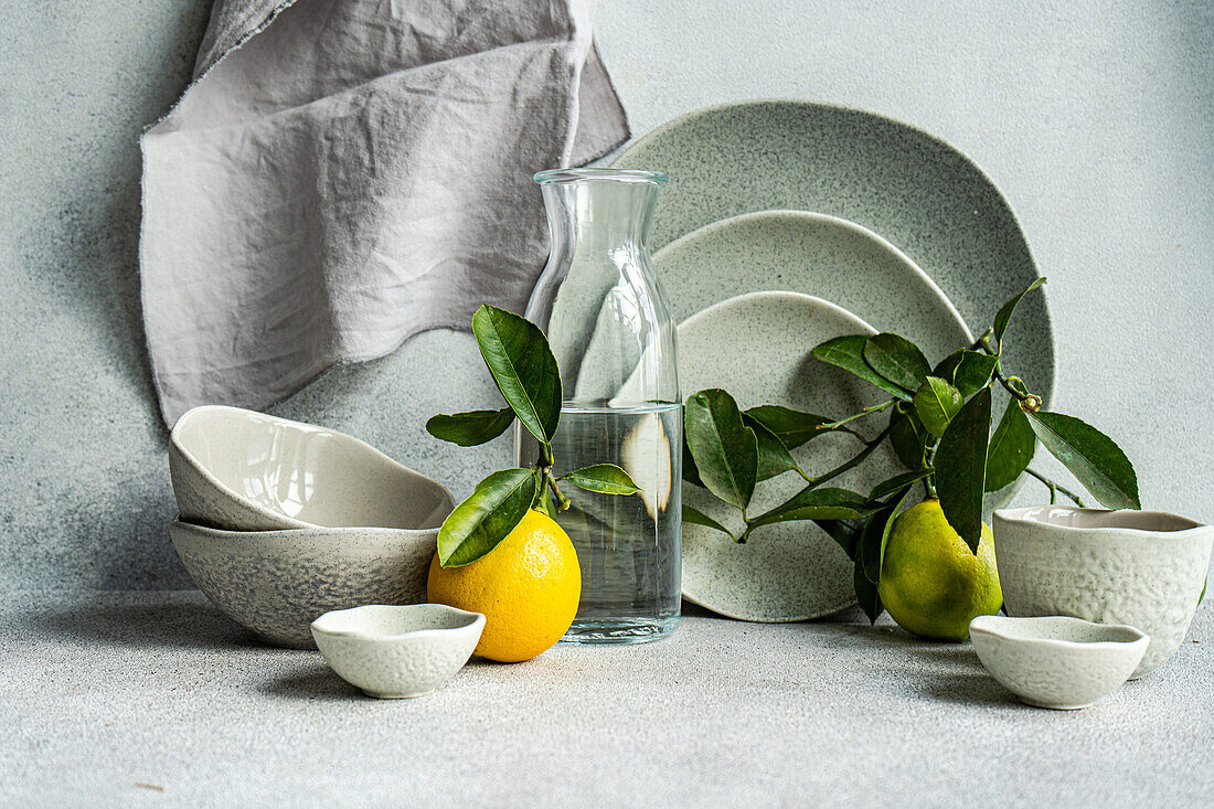 Ein raffiniert gedeckter Tisch mit feinem Keramikgeschirr, frischen Zitronen und Birnen auf einem strukturierten Leinenhintergrund