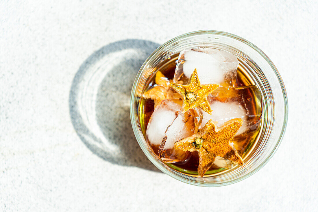 Top view of glass of whiskey with ice and orange peel placed on gray background