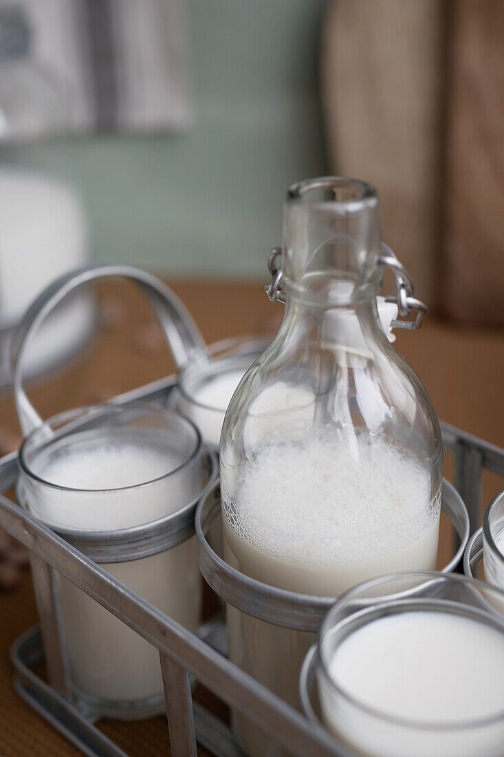 Home made organic horchata drink served in transparent glasses and bottle placed on wooden table in a rustic kitchen