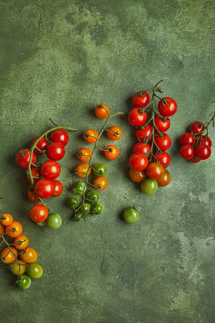 Top view of bunch of fresh ripe and unripen cherry tomatoes placed on green background