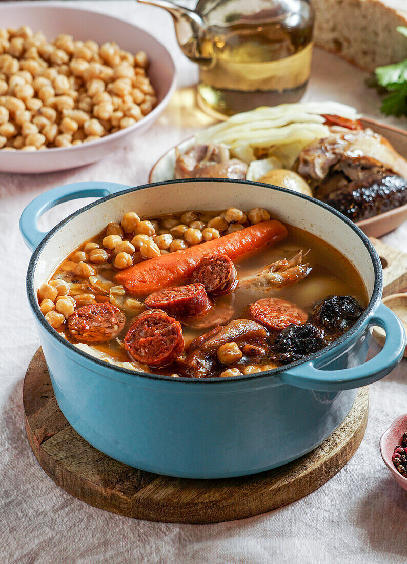 Cocido Madrileño, a traditional Spanish dish, a chickpea-based stew from Madrid with pink ceramic tiles in the background
