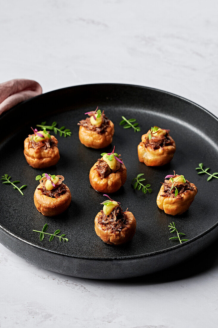 Mini Yorkshire puddings, pulled beef braised with merlot, sticky shallot marmalade, horseradish emulsion, soft herbs
