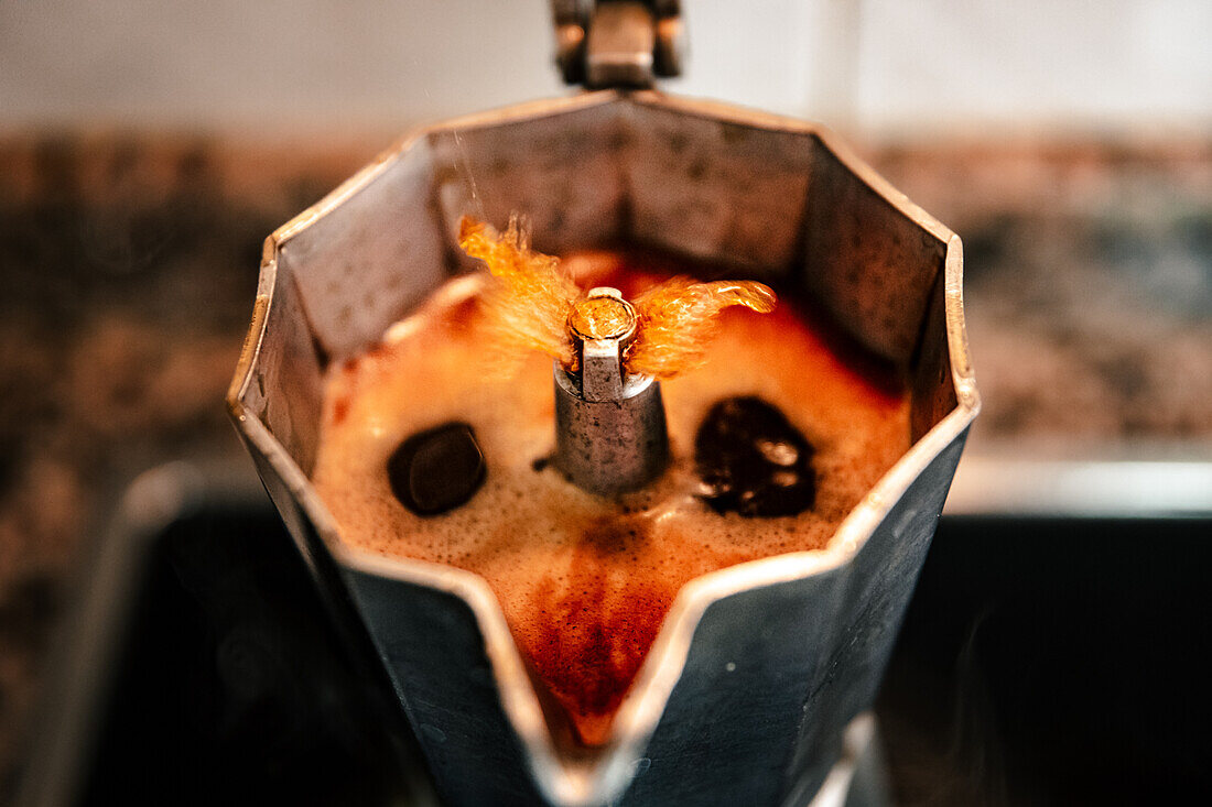 Close-up of bubbling coffee in an open stovetop espresso maker capturing the rich aroma and texture of freshly brewed Italian coffee in a homely setting