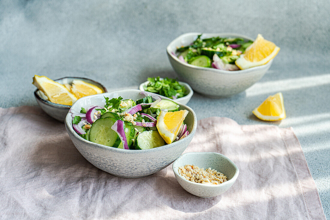 Gesunde Gemüsesalate mit Bio-Gurken, roten Zwiebeln, Koriander und gehackten Nüssen auf einem Betontisch