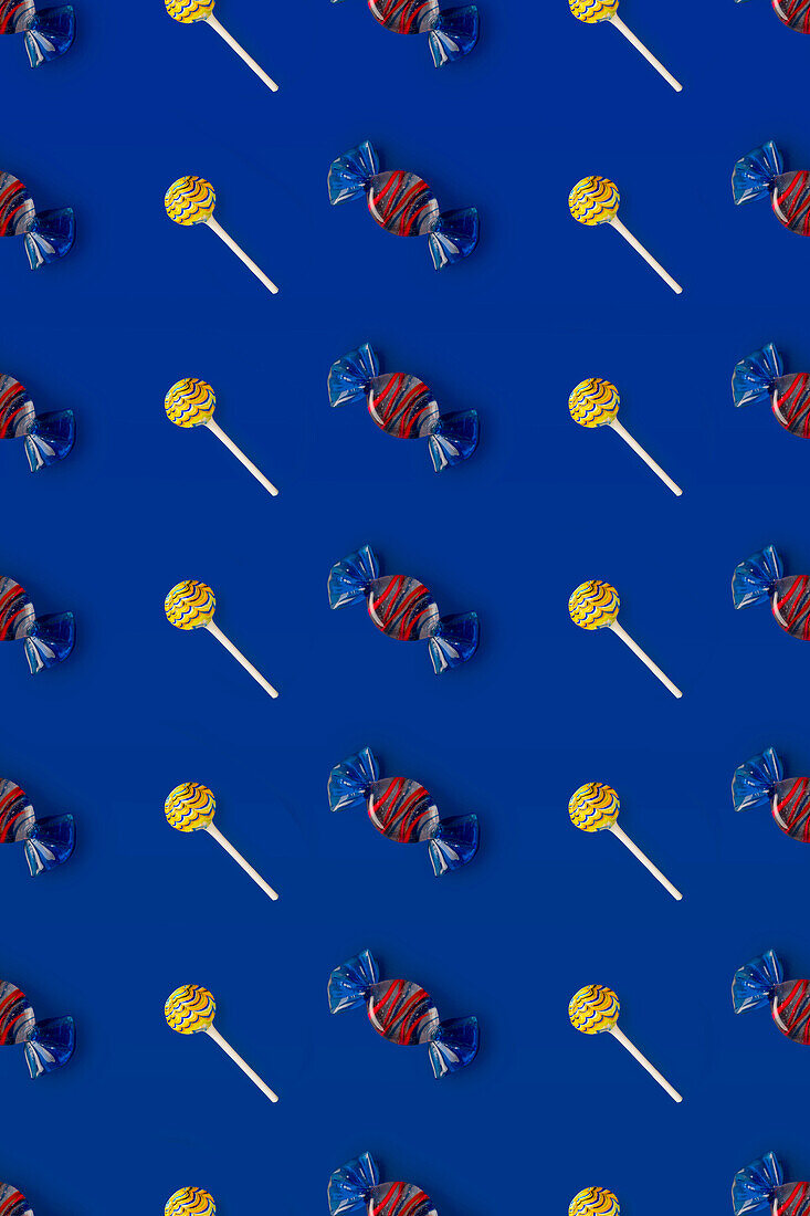 Draufsicht auf ein Muster aus ganzen süßen Kristallbonbons und Lutschern auf blauem Hintergrund