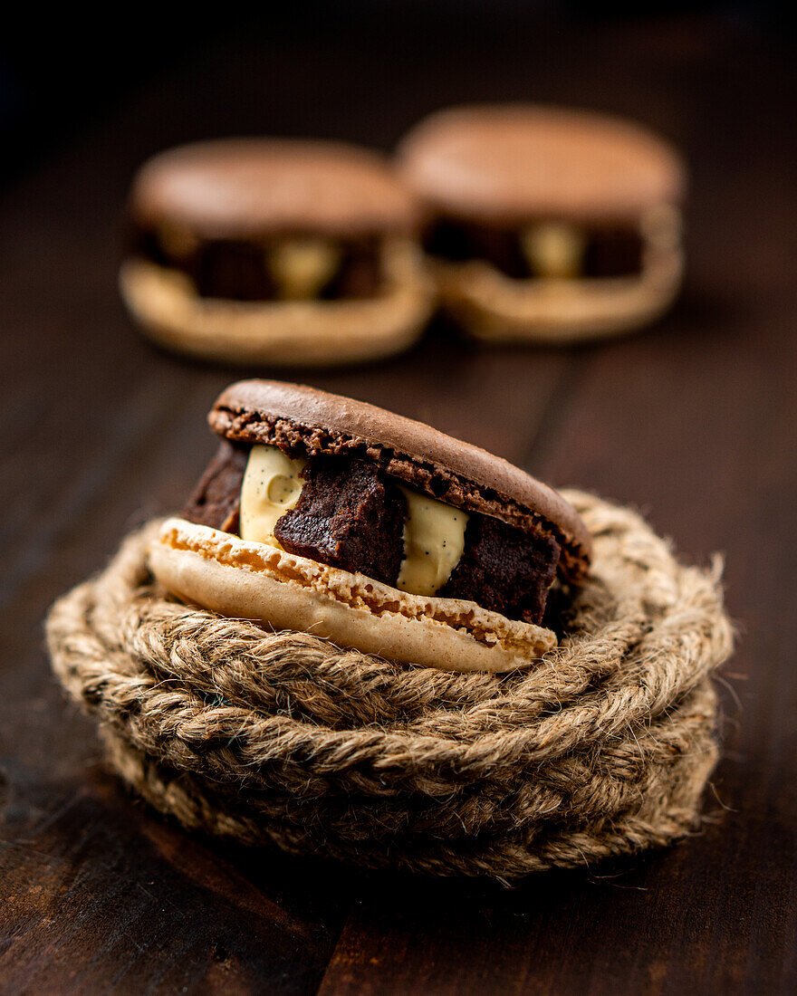 Nahaufnahme von Schokolade Brownie leckere Makronen durch Seil gegen Holztisch umgeben