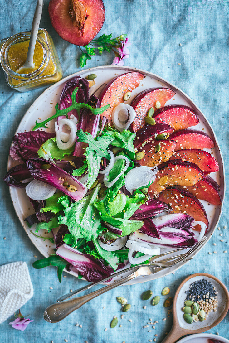Draufsicht auf einen leckeren gesunden gegrillten Pflaumen-Endivien-Salat mit verschiedenen Gemüsesorten und Gewürzen auf dem Tisch