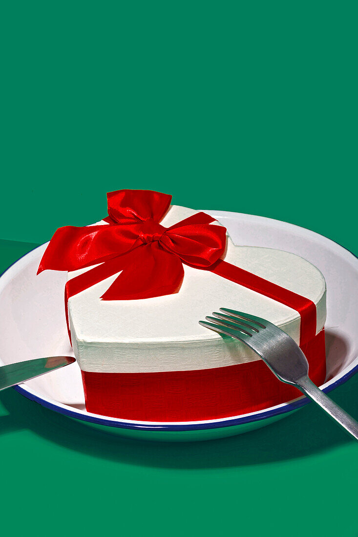 Generatives KI-Bild, das ein charmantes Valentinstagsgeschenk darstellt, eine herzförmige Schachtel mit einer roten Schleife, die elegant auf einem Teller platziert ist, um ein romantisches Abendessen darzustellen