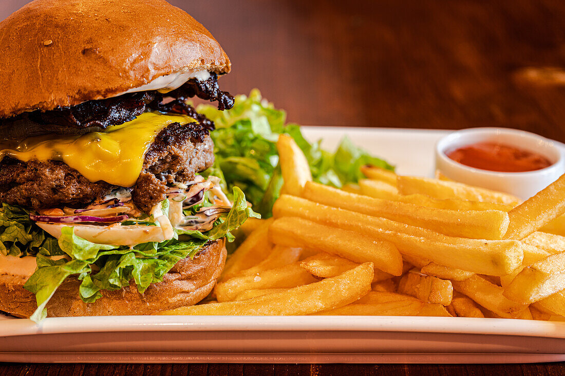 Homemade cheeseburger with cheese and vegetables served with french fries and salad