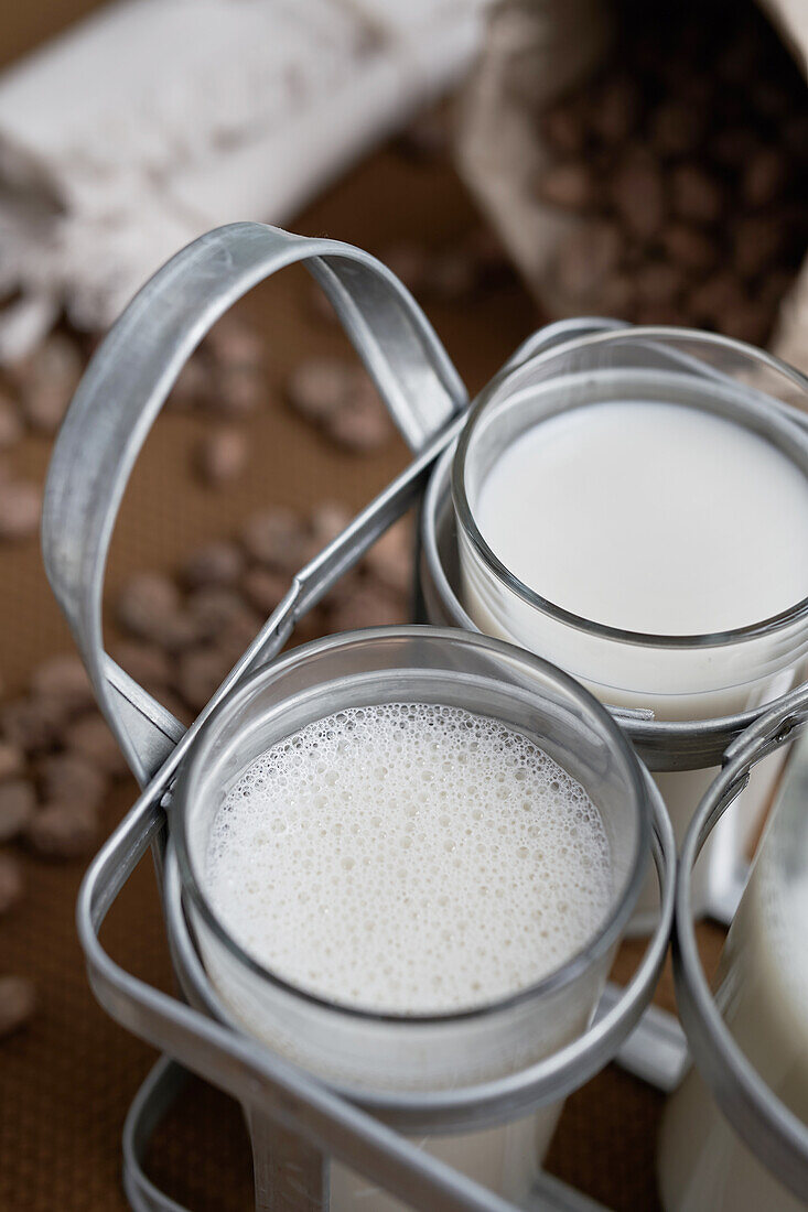 Hoher Winkel von hausgemachtem Bio-Horchata-Getränk, serviert in durchsichtigen Gläsern in einer Tüte, die auf dem Tisch neben Mandeln in einer rustikalen Küche steht