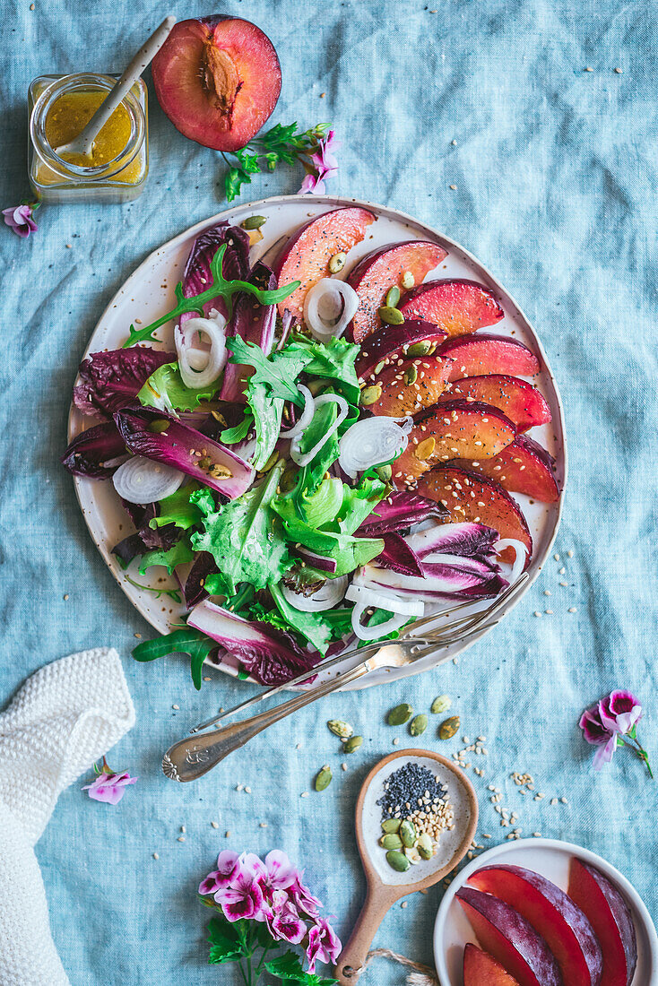 Draufsicht auf einen leckeren gesunden gegrillten Pflaumen-Endivien-Salat mit verschiedenen Gemüsesorten und Gewürzen auf dem Tisch