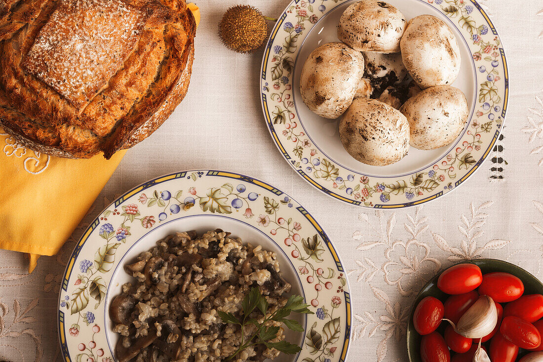 Traditional home-cooked mushroom risotto with bread on a rustic table setting, featuring fresh ingredients.