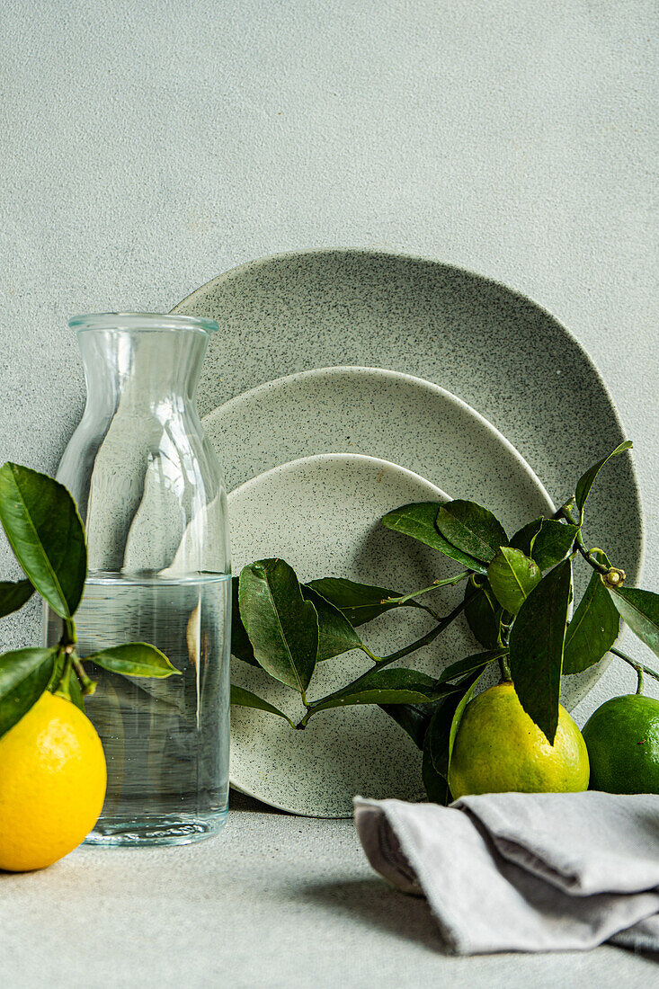 A sophisticated table setting featuring fine ceramic dishes, fresh lemons, and pears on a textured linen backdrop.