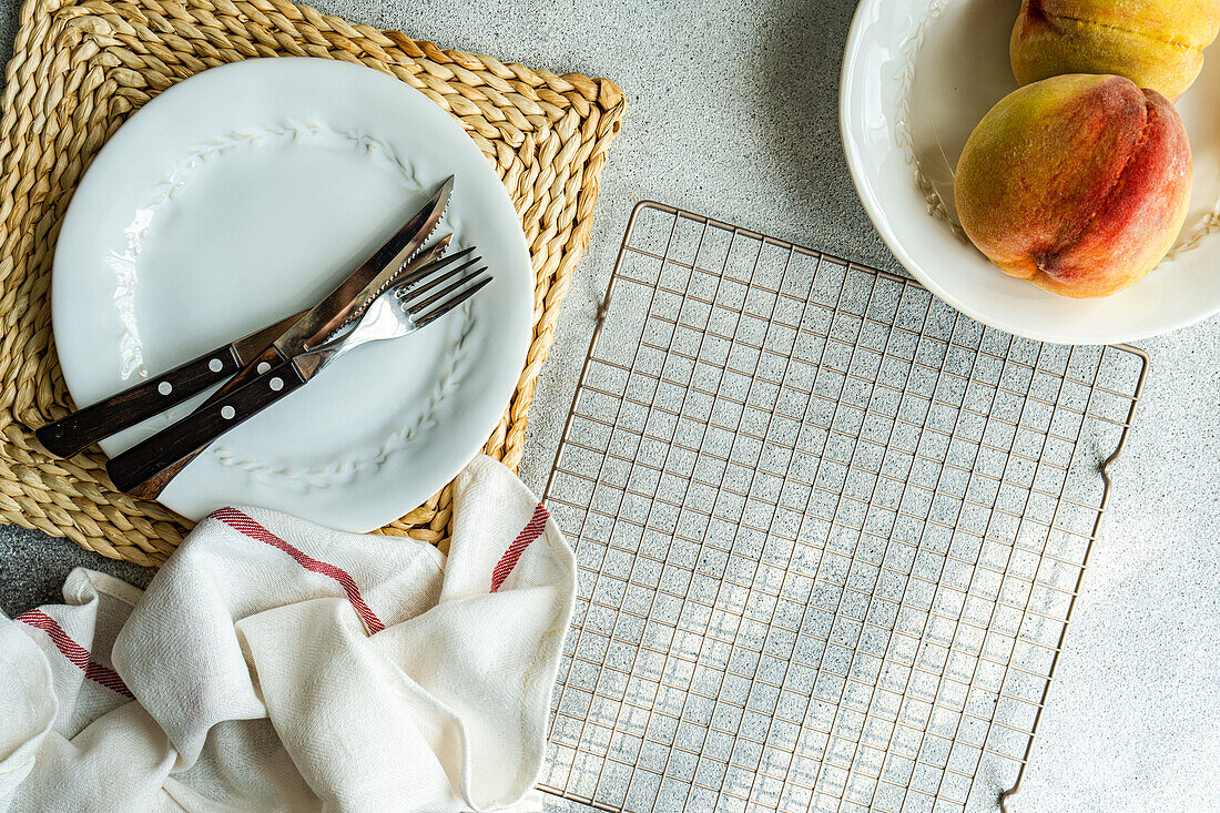 Draufsicht auf saisonale Pfirsiche, die auf einem Teller mit Gabel und Messer serviert werden, der auf dem Tisch neben einer Serviette und einem Ofengestell steht