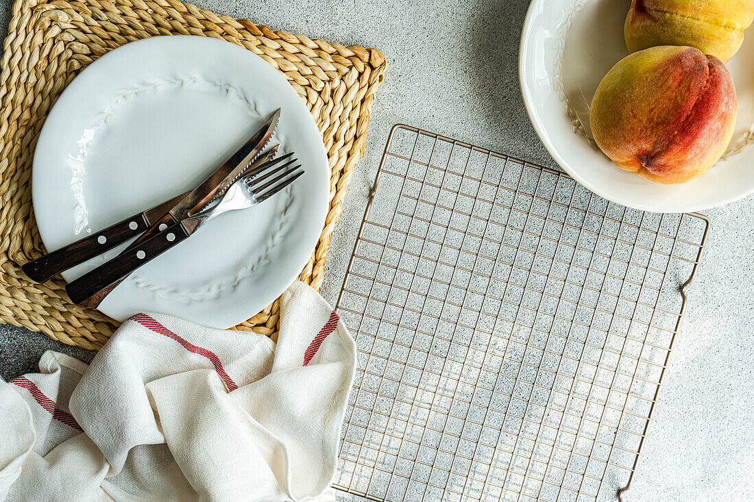 Top view of seasonal peaches served on plate near plate with fork and knife placed on table near napkin and oven rack