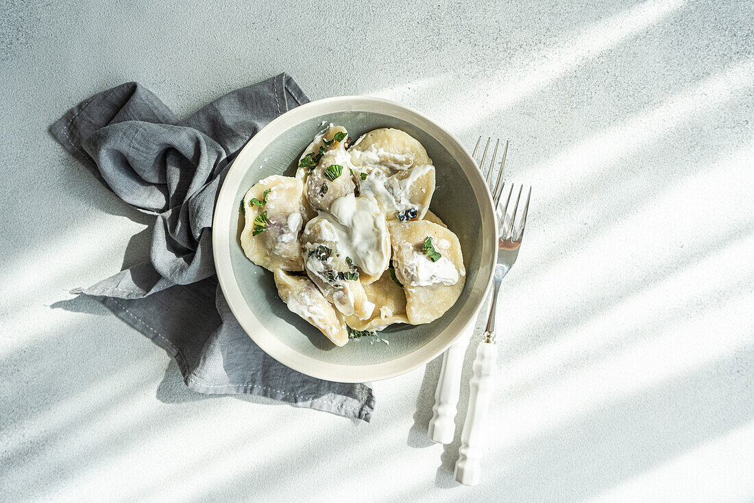 Top view of a tasty traditional Ukrainian dumplings with cherry and sour cream with mint