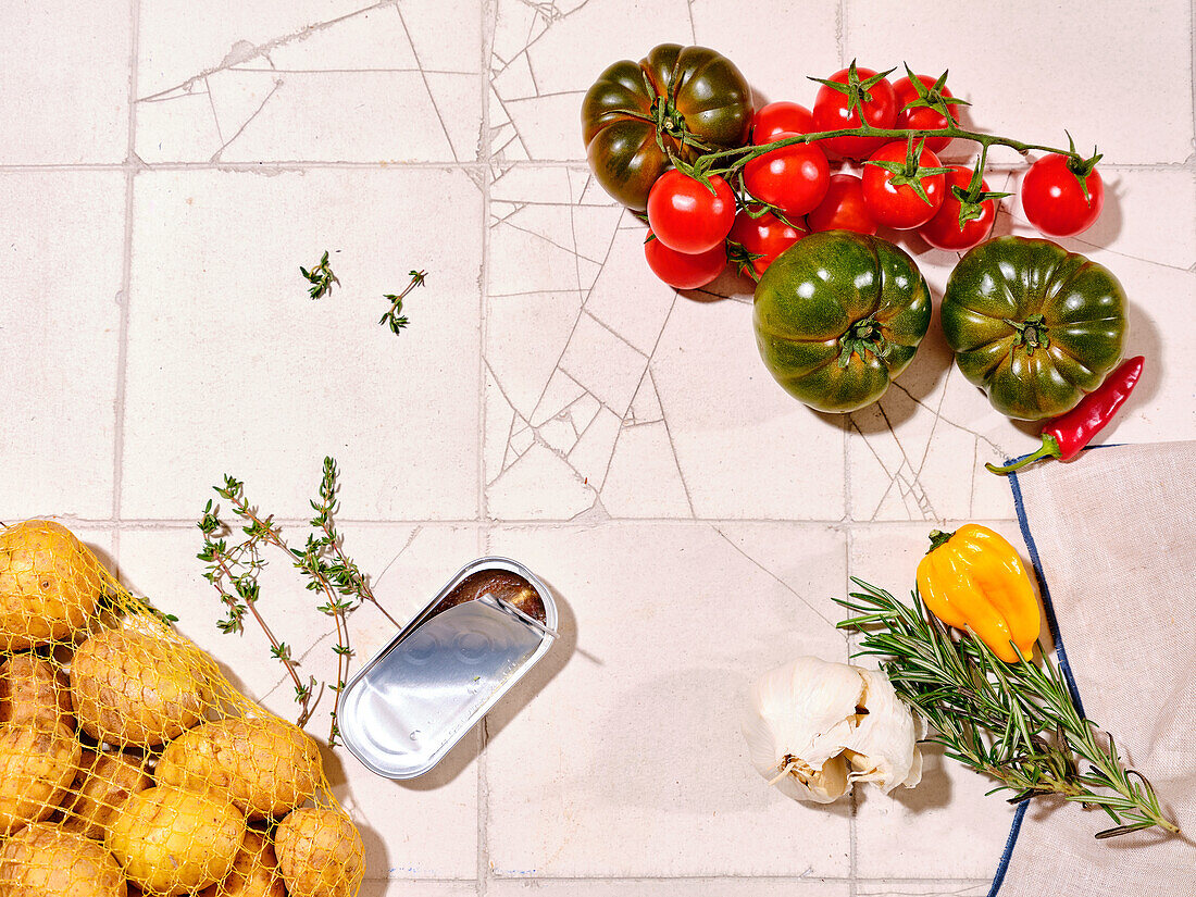 Flat lay mit frischem Gemüse auf gefliestem Hintergrund. Kochen gesundes Mittagessen mit verschiedenen Tomaten, Kartoffeln und Kräutern