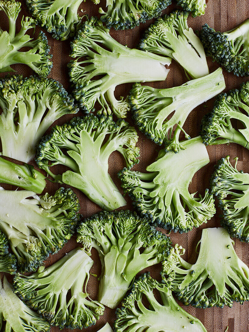 From above green broccoli stems placed on wooden background preparing to cook