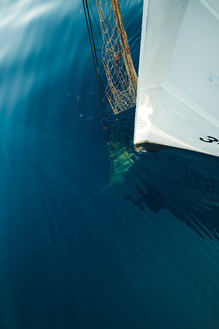 Blick von oben auf ein schwimmendes Segelboot mit Fischereigerät auf offenem Meer in Soller bei den Balearen auf Mallorca bei der traditionellen Fischjagd