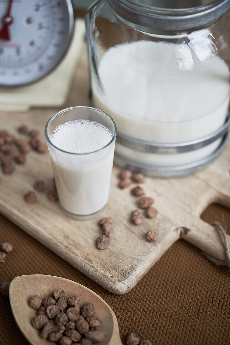 High angle of home made organic horchata drink served in a modern transparent glass near almonds on table in a rustic kitchen