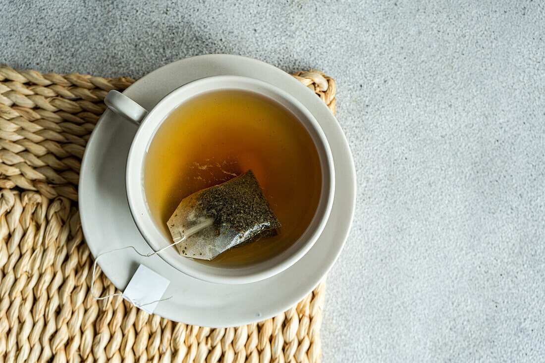 From above of white stylish cup of hot aromatic Green tea with tag placed on with on concrete table