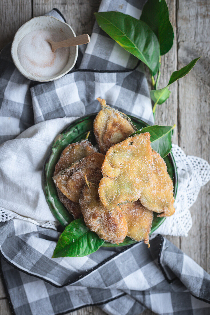 Draufsicht auf einen Teller mit Paparajotes, einem typischen Dessert aus Murcia in Spanien, das mit Zitronenblättern zubereitet und mit Zucker bestreut wird