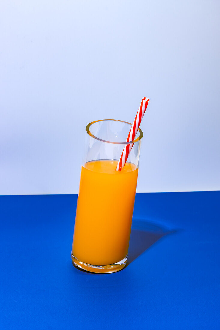 Nahaufnahme eines Glases mit frischem Orangensaft-Cocktail auf blauem Hintergrund