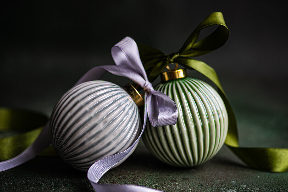 Balls as sign of Christmas decorated with ribbons and placed on green surface against dark background