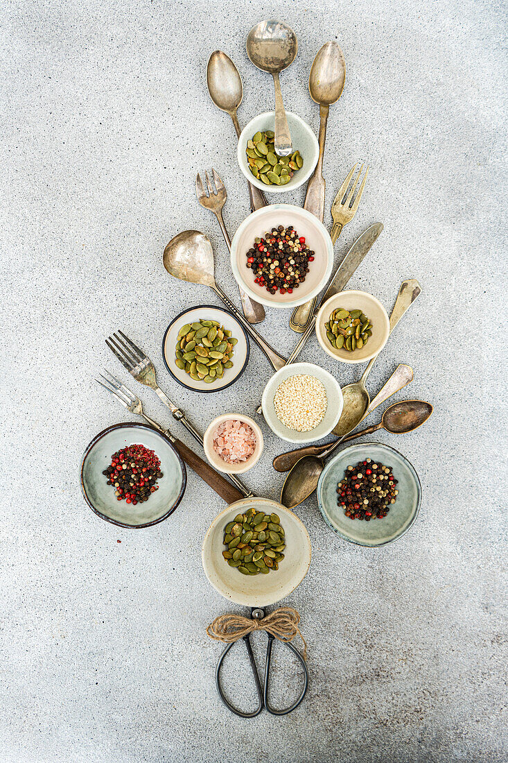 An artistic flat lay of antique kitchen utensils and assorted spices and seed in small bowls in a christmas tree shape, perfect for culinary themes.