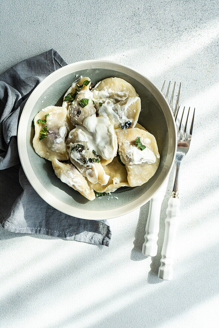 Top view of a tasty traditional Ukrainian dumplings with cherry and sour cream with mint