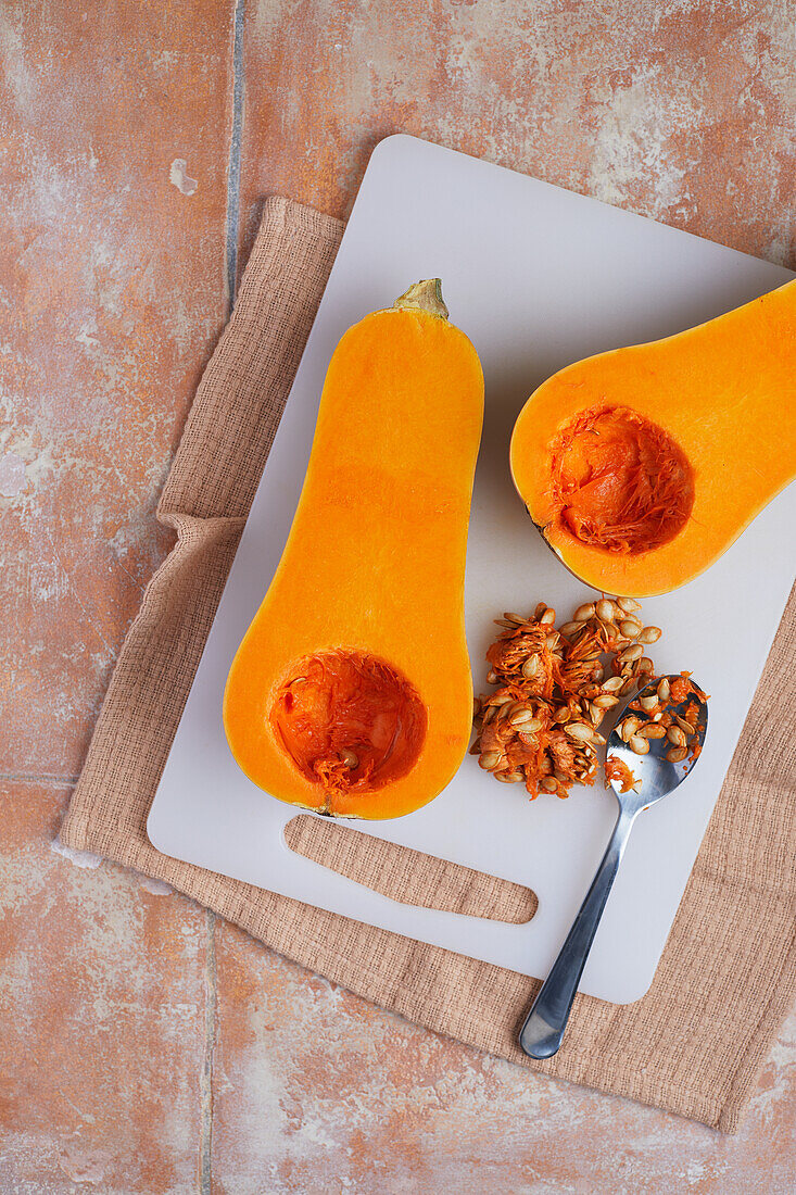 From above of juicy pumpkin split in half orange with seeds and flesh placed on table