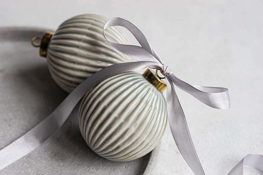 Focused of balls decorated with satin ribbon as symbol of Christmas time placed on gray surface