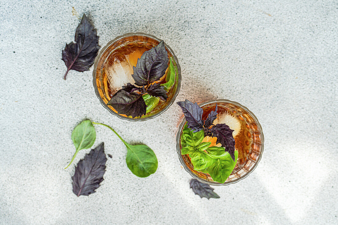 Glass of cocktail with tonic and fresh basil herb leaves