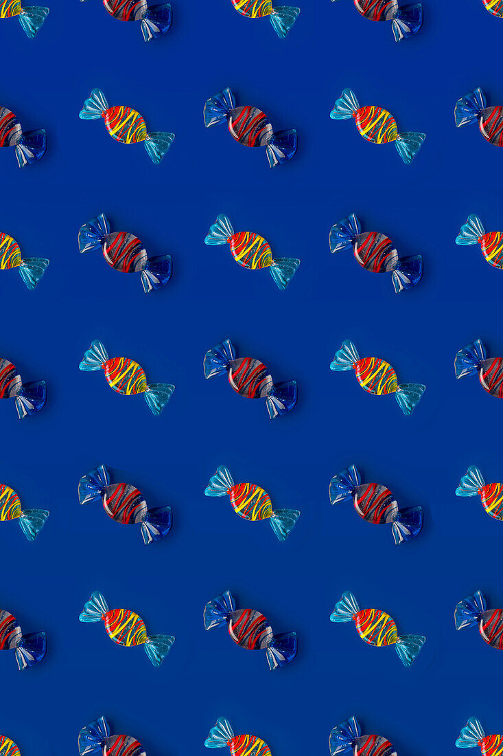 Top view of pattern of whole sweet crystal candies arranged on blue background