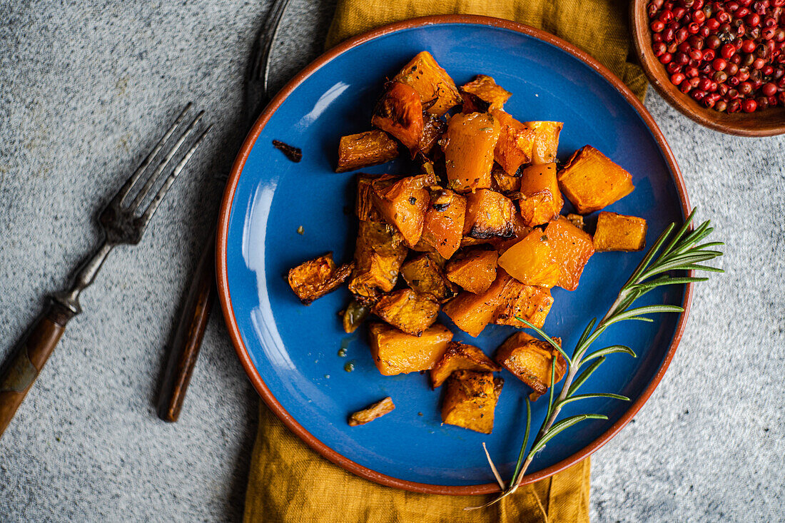 Baked spicy pumpkin cubes served on blue ceramic plate on the table