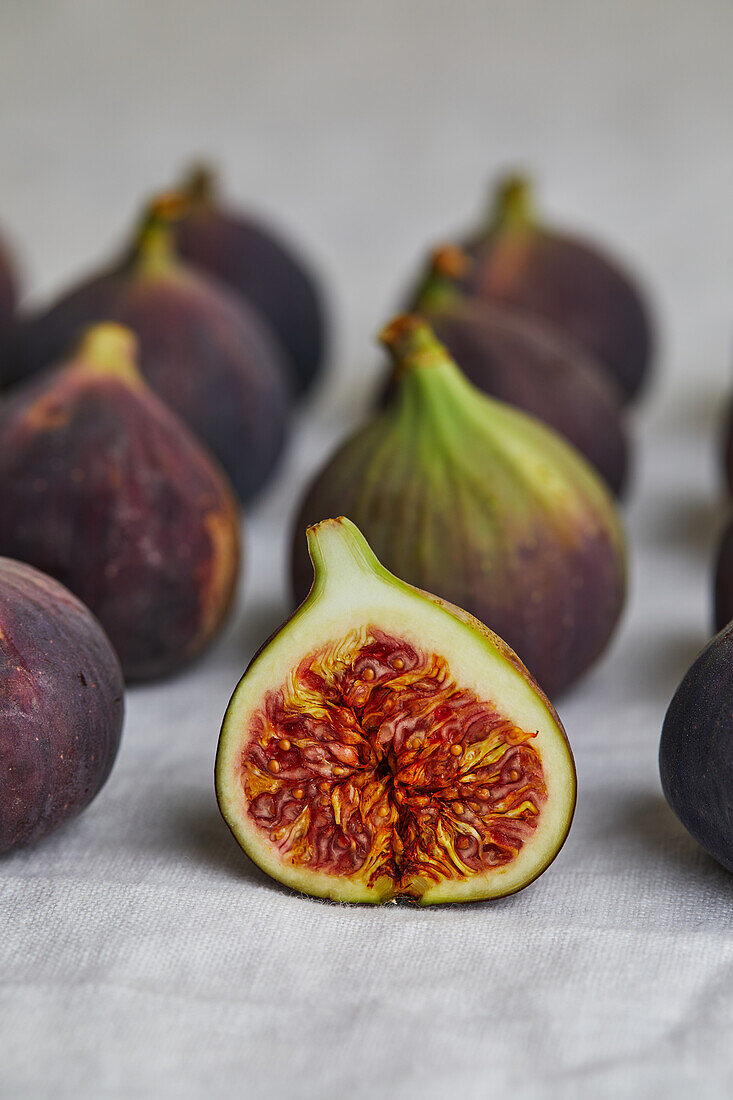 Closeup of minimalist blurred composition with fresh figs placed on gray napkin surrounded by blurred rows of fresh figs